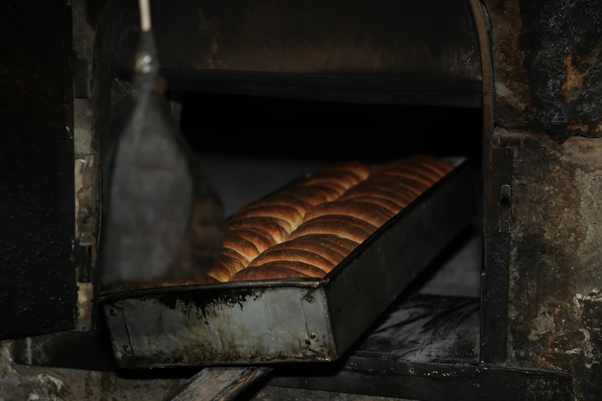 A tray of bread baking inside a traditional brick oven.