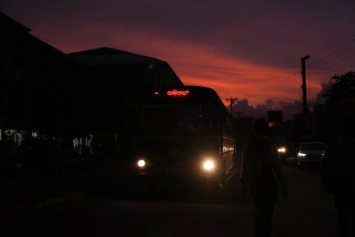 Traffic passing through Gampaha beneath a glowing sunset sky.