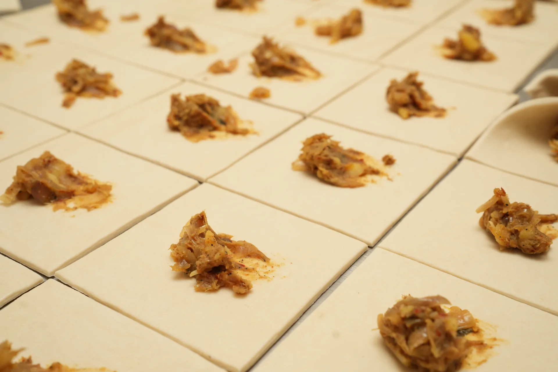 Portions of pastry filling arranged on squares of dough.